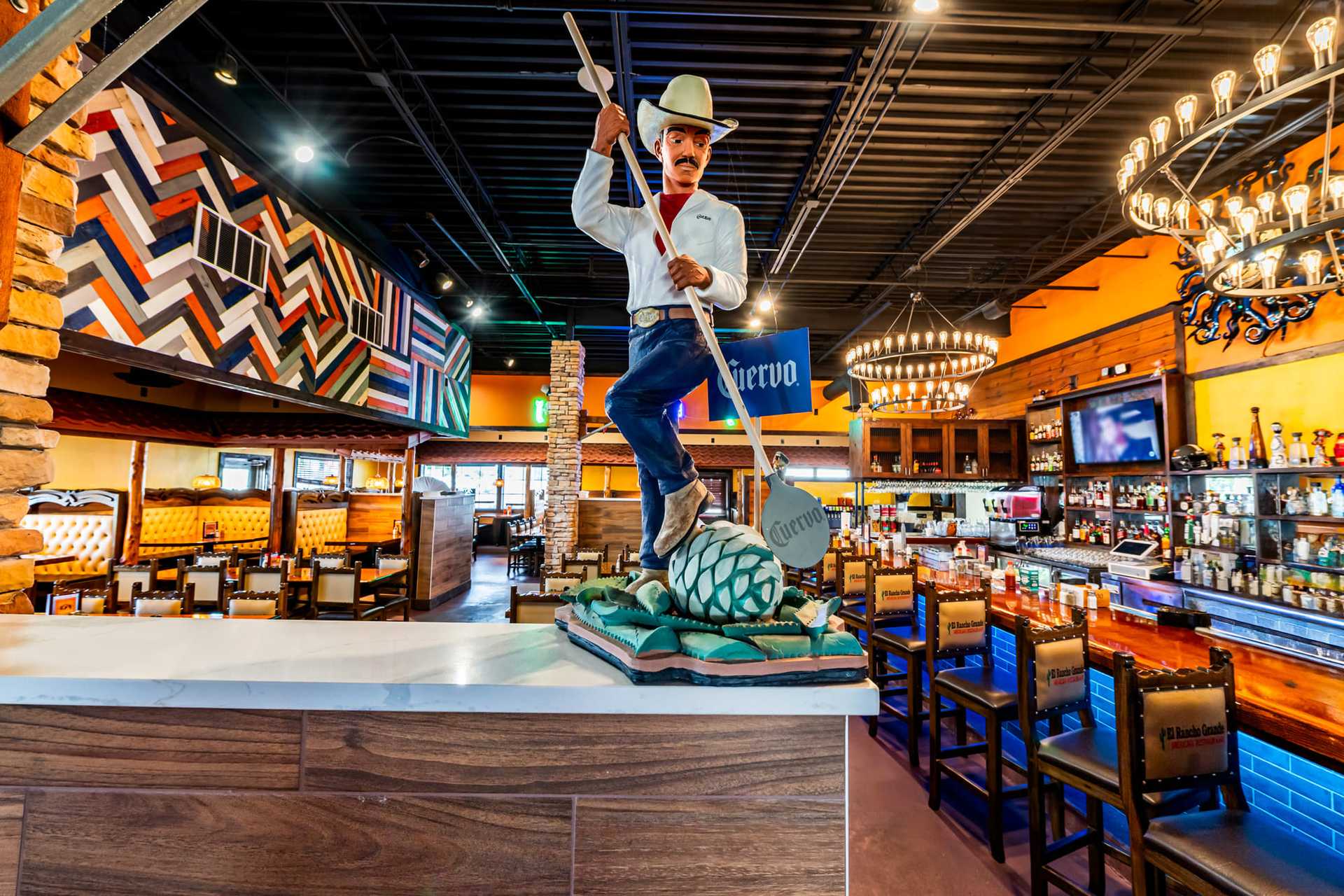Statue of man with agave plant in vibrant, rustic restaurant interior.
